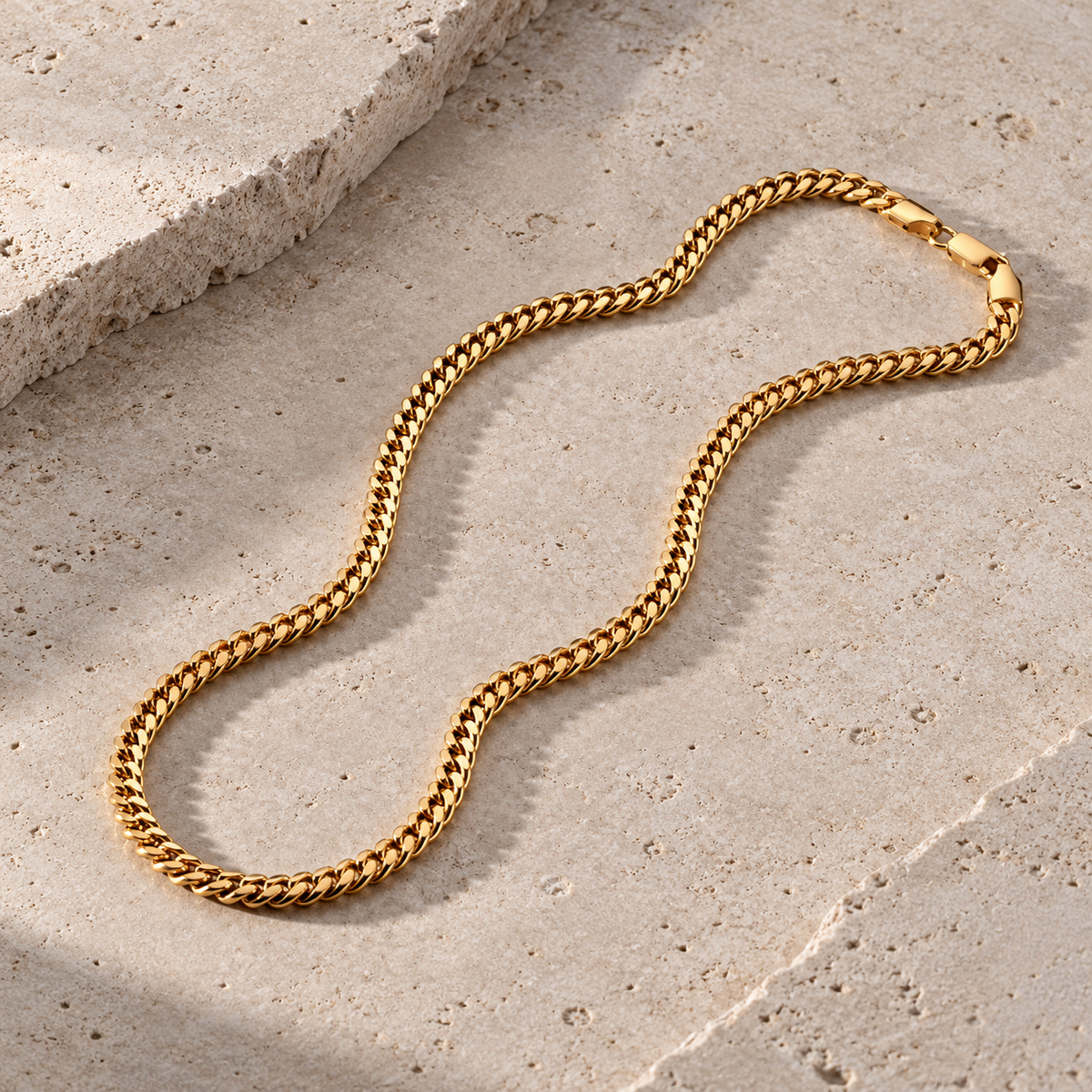 Cadena Cuban Link dorada de acero inoxidable sobre piedra clara